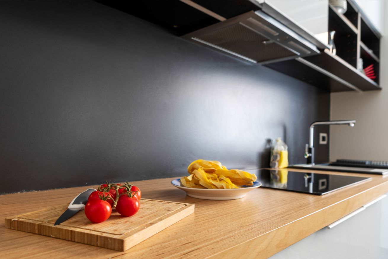 Un plan de travail de cuisine avec une planche à découper, des tomates et une assiette de chips.