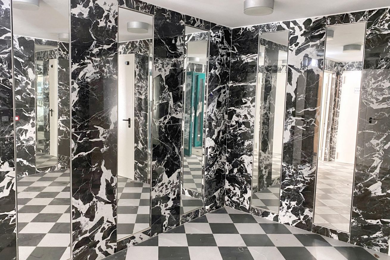 A checkered floor with mirrored walls and a door.