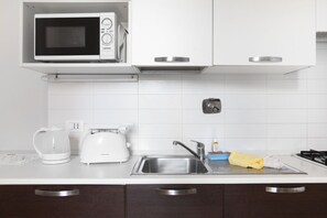 A modern kitchen with a microwave, toaster, kettle, and sink.