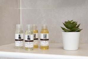 Four bottles of Fattoria di Belcantio shampoo on a shelf with a potted succulent plant.