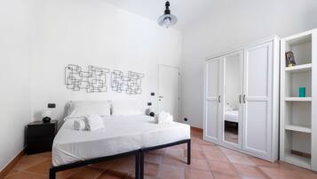 Een slaapkamer met een bed, nachtkastje, kledingkast en een kunstwerk aan de muur.