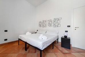 A bedroom with a bed, a nightstand, a wall art piece, and a door.