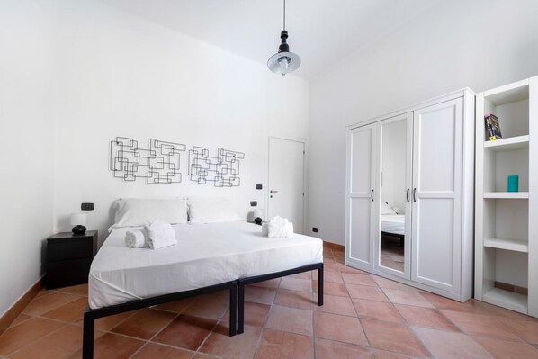 Ein Schlafzimmer mit Bett, Nachttisch, Kleiderschrank und einem Wandbild.