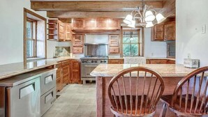 A kitchen with wooden cabinets, a large island with chairs, and a hanging light fixture. - A cozy, beautifully renovated 1829 farmhouse (Mechanicsburg)
