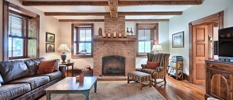 A cozy living room with a fireplace, leather sofa, wooden coffee table, and a television.