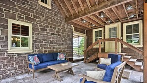 A stone-walled room with a wooden staircase, blue upholstered furniture, and a wooden table. - A cozy, beautifully renovated 1829 farmhouse (Mechanicsburg)
