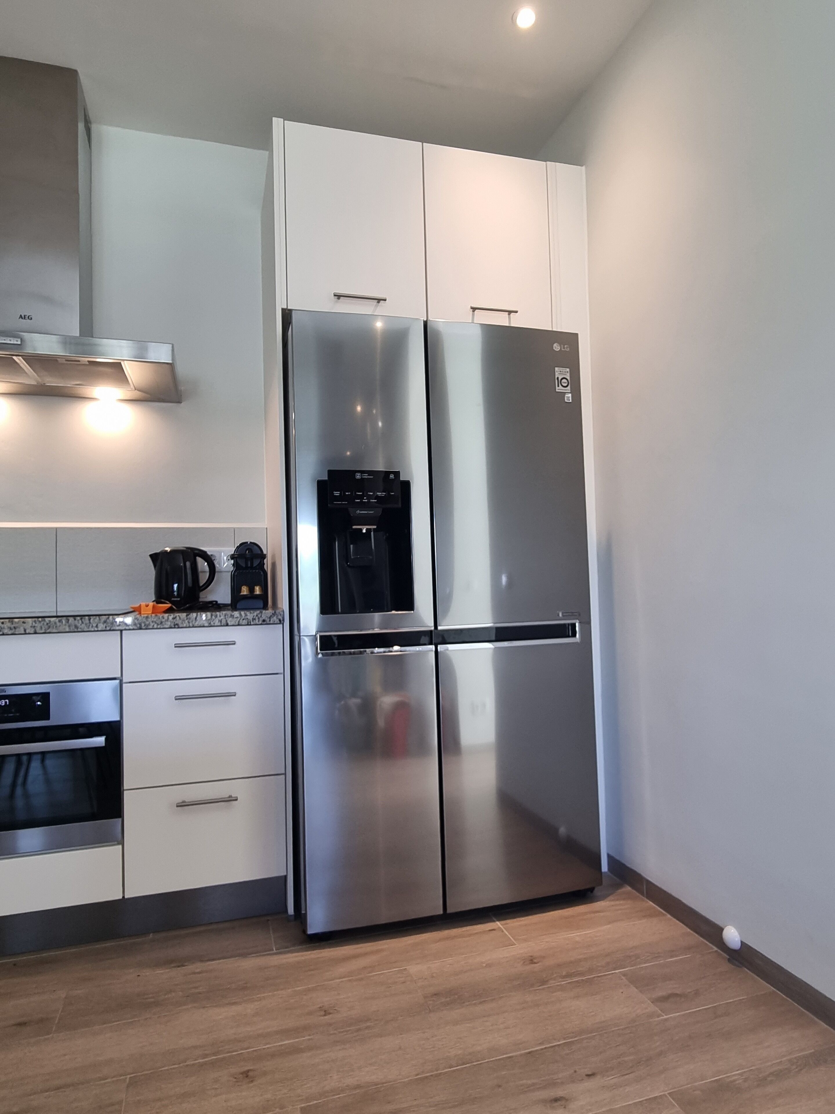 Una cucina moderna con frigorifero in acciaio inox, forno integrato e macchina da caffè sul piano di lavoro.