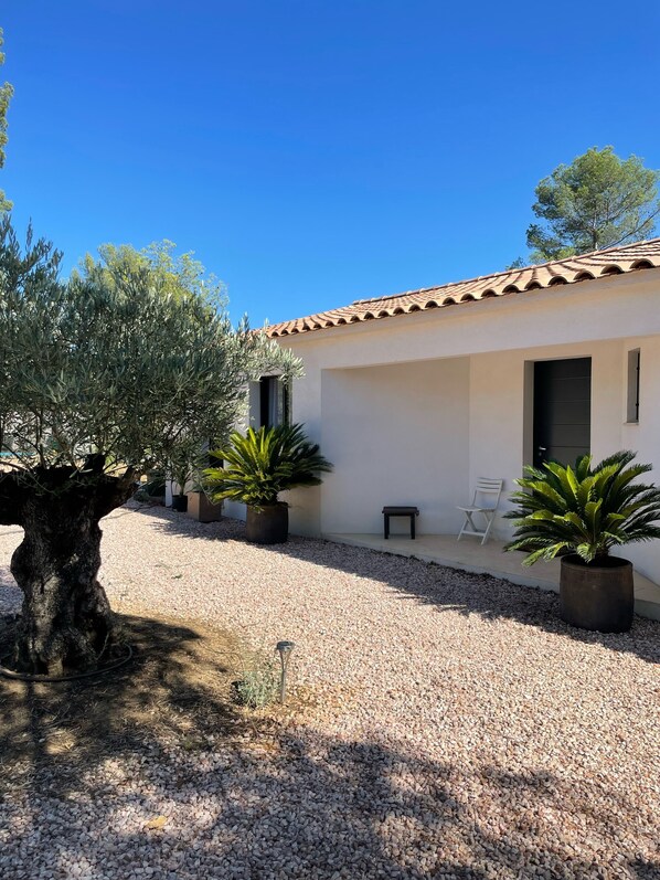 A building with a tiled roof, a gravel driveway, and potted plants.