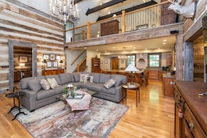 A spacious living area with a large sectional sofa, a coffee table, and a chandelier.