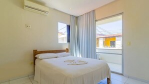 Une chambre d’hôtel équipée d’un lit, d’un appareil de climatisation, d’une fenêtre avec des rideaux et offrant une vue sur l’extérieur.