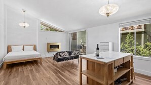 Een moderne slaapkamer met een bed, een bank, een televisie, een open haard en een eethoek met een tafel en stoelen.