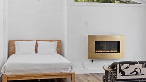 Een slaapkamer met een bed, een wandvuurplaats en een raam.