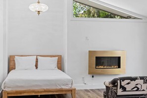 Une chambre à coucher avec un lit, une cheminée fixée au mur et une fenêtre.