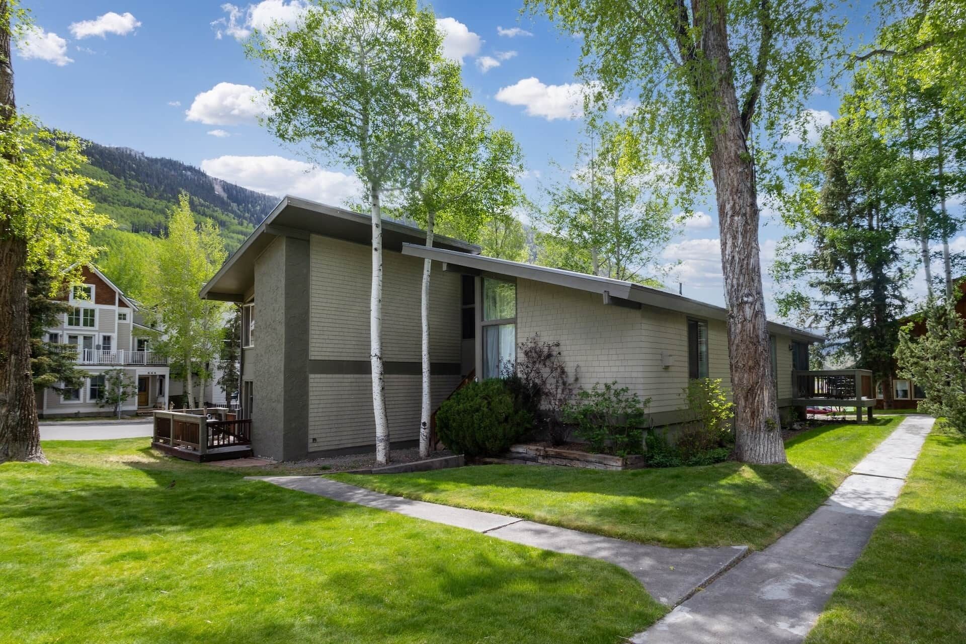 A two-story house with a front porch, a small deck, and a well-maintained lawn.