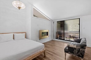 Un dormitorio con cama, sofá, chimenea y un ventanal grande.