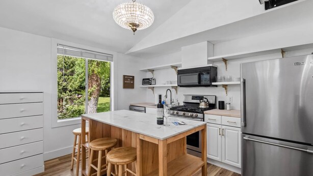 Een moderne keuken met een centraal eiland, barstoelen, een roestvrijstalen koelkast en uitzicht op de omgeving.