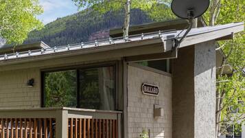 A building with a satellite dish, a sign reading 'BALLARD,' and a view of a forested mountain.