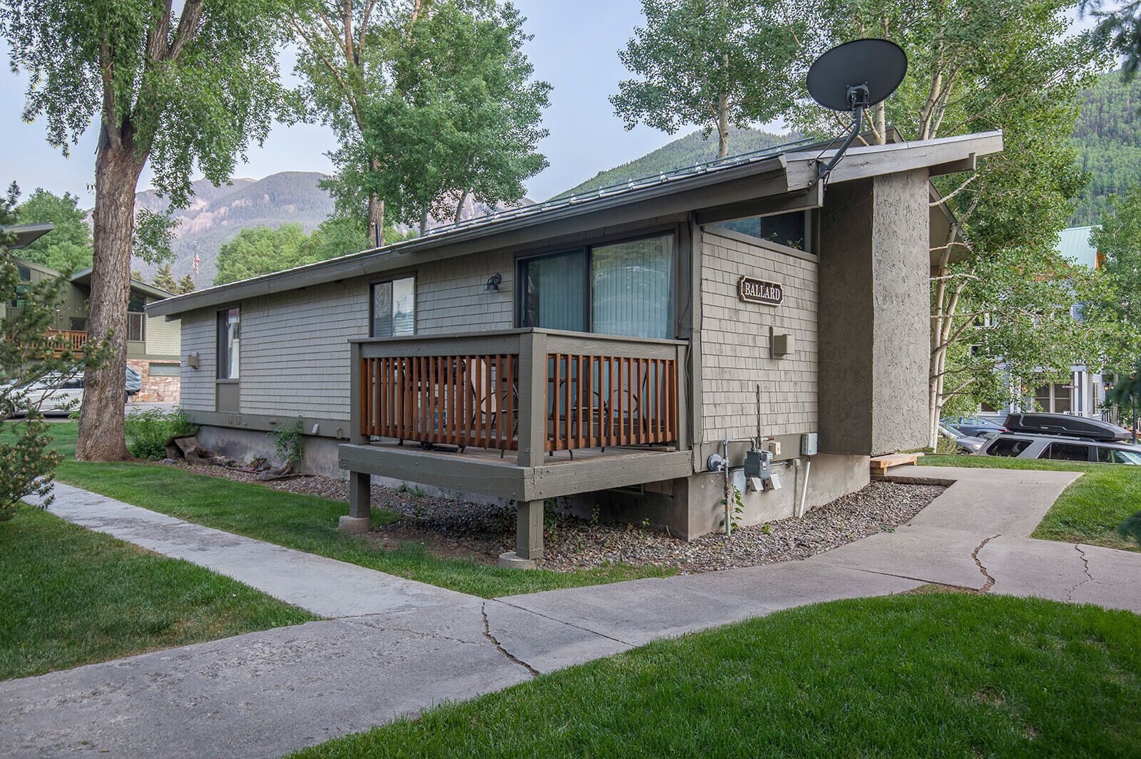 A modern single-story house with a balcony, satellite dish, and a visible garage.