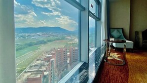 Una habitación con un ventanal amplio que ofrece vistas panorámicas de la ciudad, una mesa redonda y una silla.