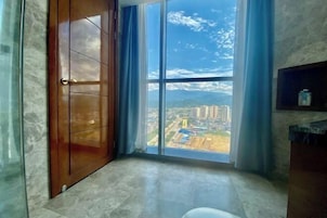Una habitación con un ventanal amplio que ofrece vistas a la ciudad, una puerta de madera y un piso de mármol.