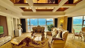 A luxurious living room with ornate furniture, a large window offering a mountain view, and a high ceiling with wooden beams. - Hongbo Hotel (Gengma)