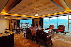 Amplia habitación con un gran ventanal que ofrece vistas a montañas, un mostrador de recepción y muebles de madera tradicionales.