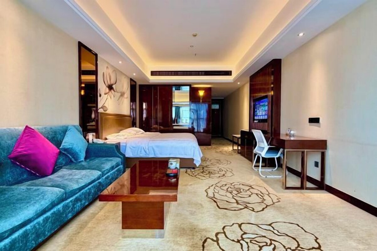 A hotel room with a bed, a sofa, a desk, and a chair.