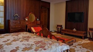 Un dormitorio con una cama grande, muebles de madera, un televisor y paneles de madera en la pared.