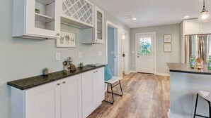 Une cuisine moderne avec des meubles blancs, un plan de travail foncé et un réfrigérateur en acier inoxydable.