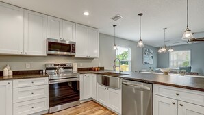 A modern kitchen with white cabinets, stainless steel appliances, and a wooden floor. - Seascape - Yellow🌼PRIVATE POOL✔️3-MIN WALK to BCH✔️ (Butler Beach)