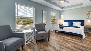 A bedroom with a bed, two chairs, a ceiling fan, and large windows. - Seascape - Yellow🌼PRIVATE POOL✔️3-MIN WALK to BCH✔️ (Butler Beach)
