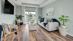 A living room with a sofa, two chairs, a coffee table, and a TV mounted on the wall. - Seascape - Blue🐬 PRIVATE POOL✔️3-MIN WALK to BCH✔️ (Butler Beach)