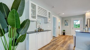 A modern kitchen with white cabinetry, a wooden floor, and a large potted plant. - Seascape - Blue🐬 PRIVATE POOL✔️3-MIN WALK to BCH✔️ (Butler Beach)