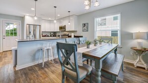 A modern kitchen with white cabinets, a stainless steel refrigerator, and a central island with bar stools. - Seascape - Blue🐬 PRIVATE POOL✔️3-MIN WALK to BCH✔️ (Butler Beach)