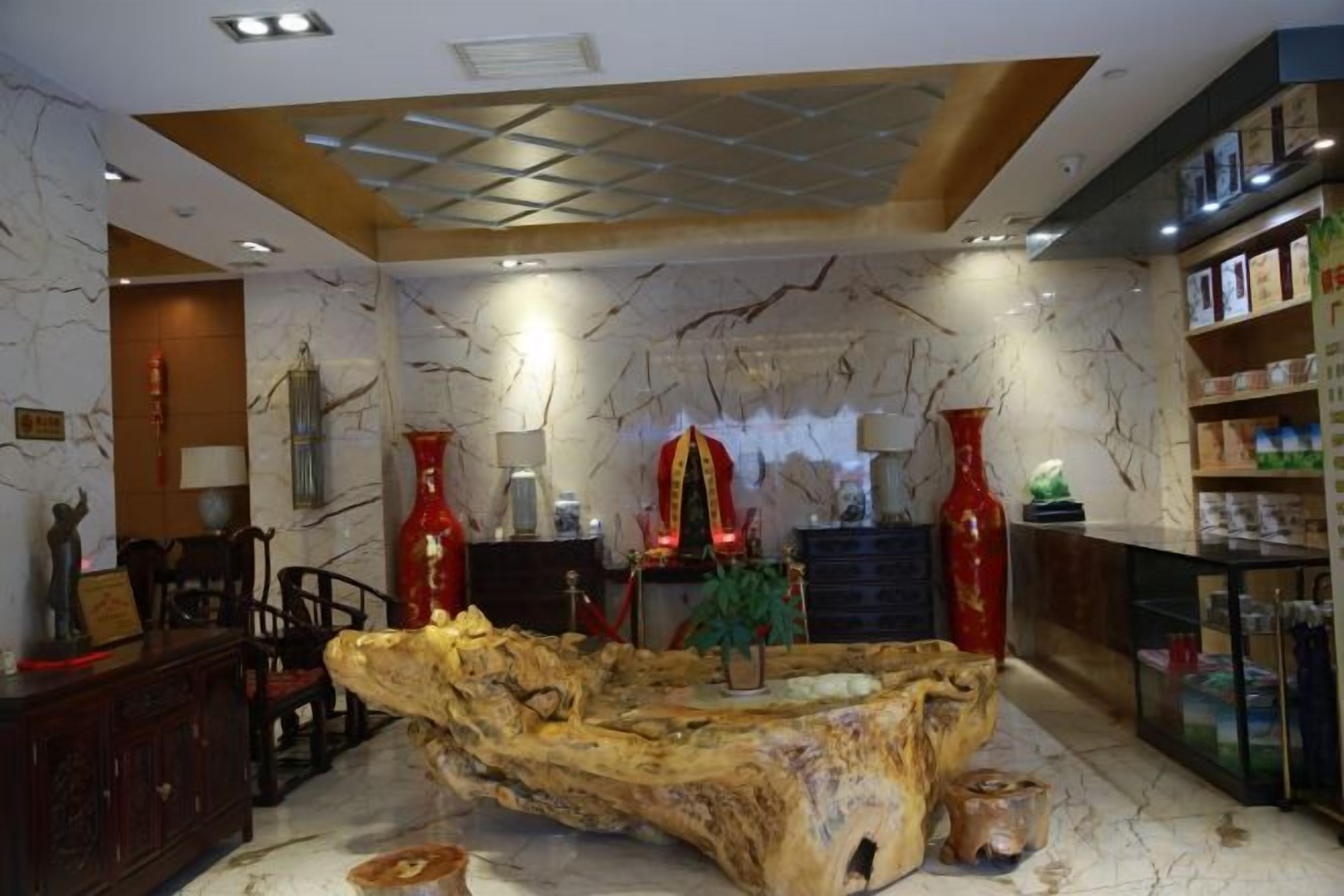 A room with a central wooden sculpture, a reception desk, and a bookshelf.