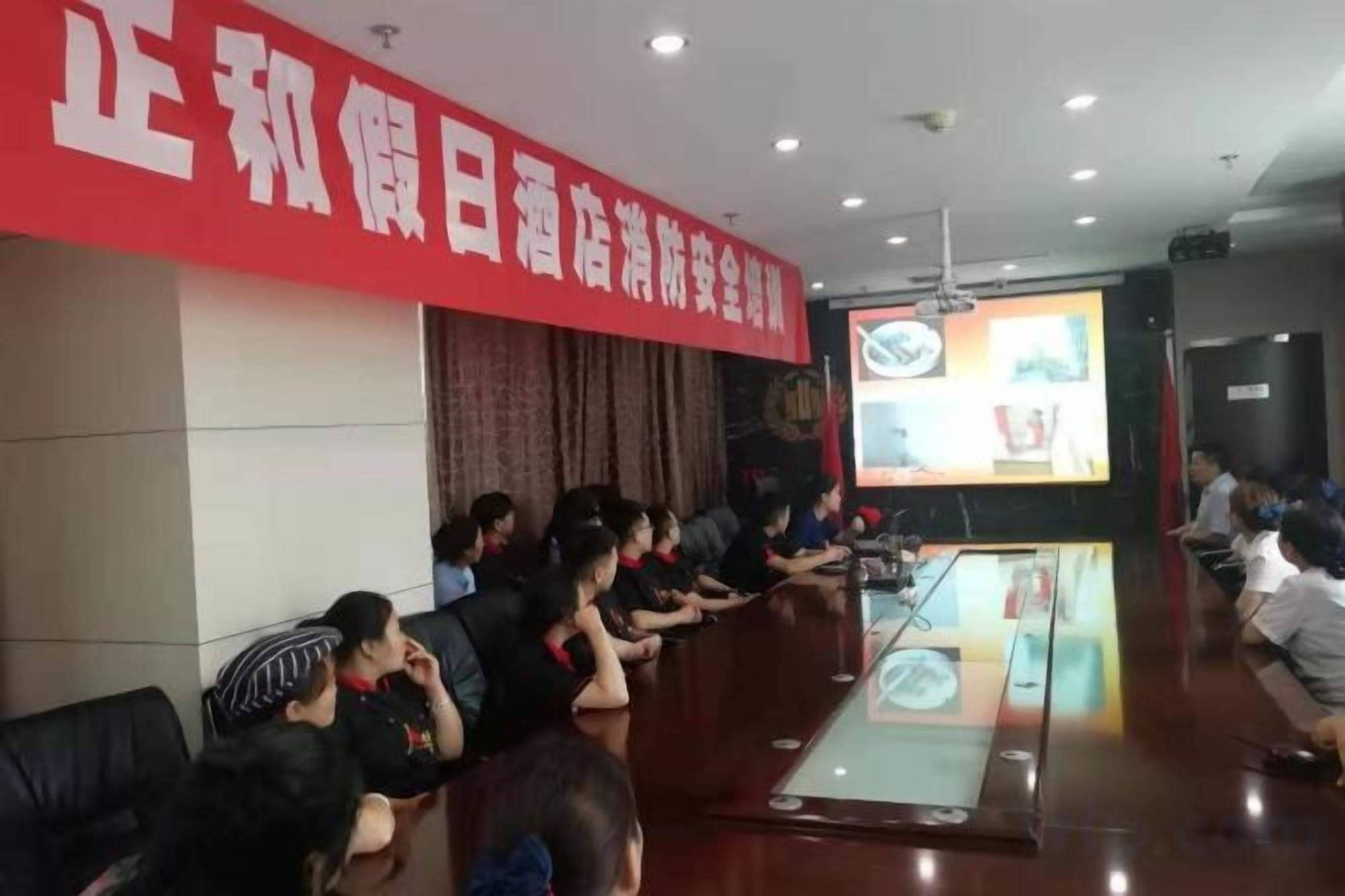 A conference room with a long table, chairs, and a large screen.