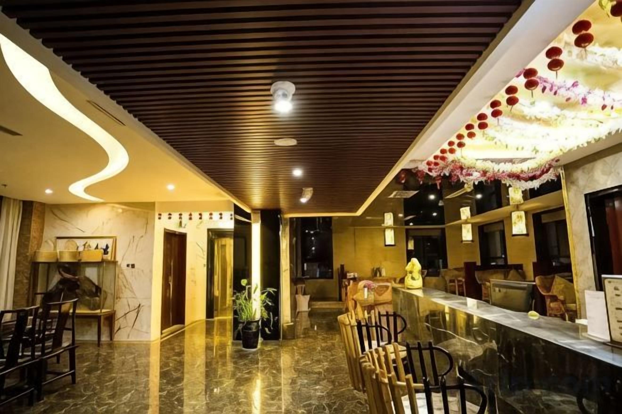 A hotel lobby with a marble floor, wooden ceiling, and a reception desk.