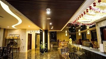 A hotel lobby with a marble floor, wooden ceiling, and a reception desk.