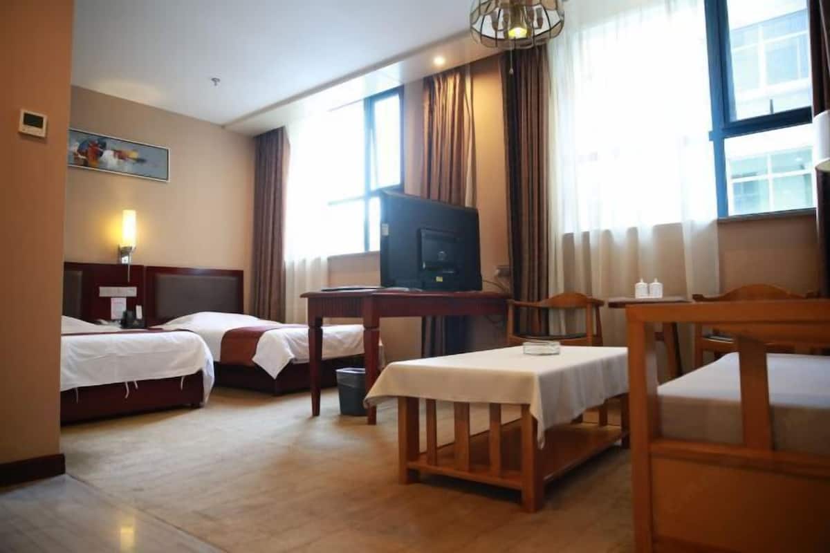 A hotel room with two beds, a television, a table, and a chair.