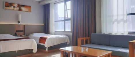 A hotel room with two beds, a sofa, a wooden table, and a painting on the wall.