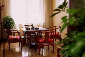 Un comedor con una mesa, cuatro sillas, una planta en maceta y una ventana con cortinas.