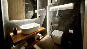 Un bagno moderno con uno specchio grande, un lavabo a incasso, un water e una doccia.