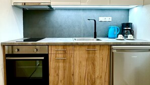 Una cucina funzionale con mobili in legno, forno integrato, lavastoviglie, lavello e macchina per il caffè.