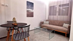 Un soggiorno moderno con un tavolino in vetro, un tavolo da pranzo rotondo con sedie, un divano e un quadro appeso al muro.