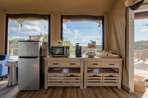 Une cuisine de taille réduite, équipée d’un réfrigérateur, d’un four à micro-ondes et de meubles de rangement en bois.