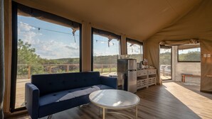 A room with a sofa, a round table, and a refrigerator.
