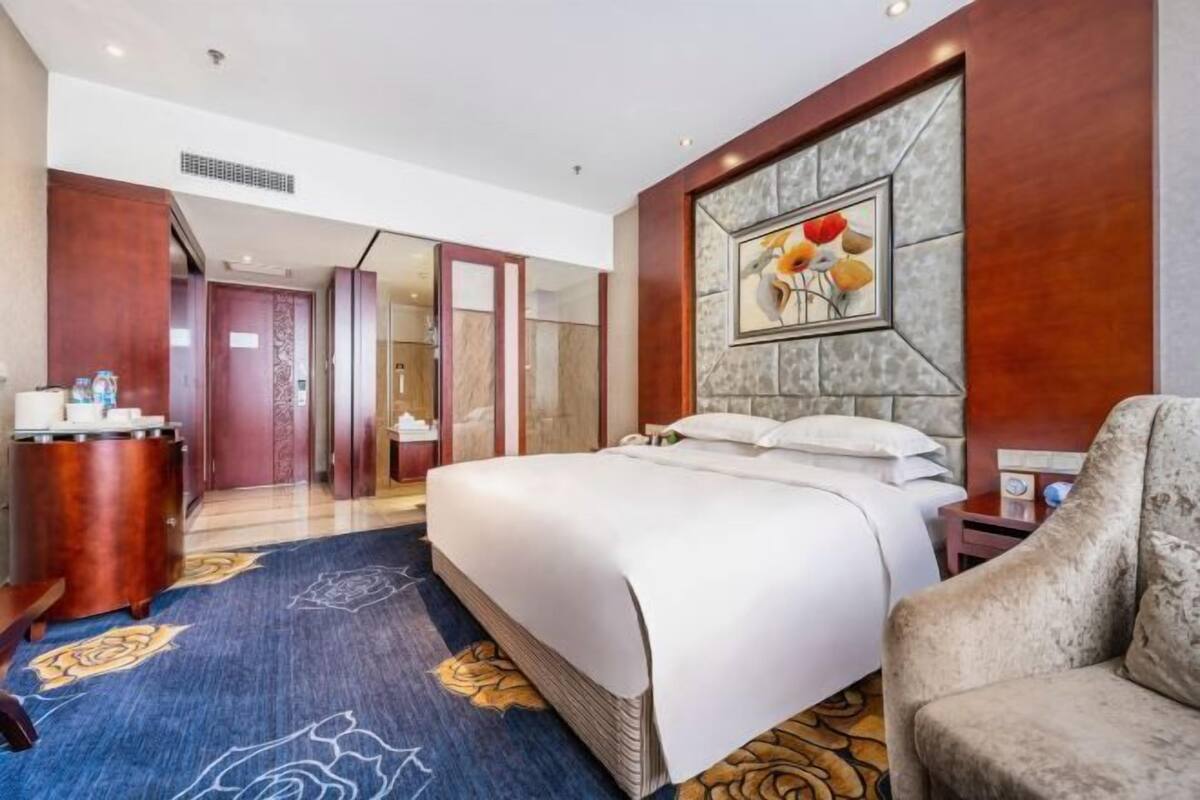 Een hotelkamer met een groot bed, een bureau met stoel, een kaptafel en een groot raam.
