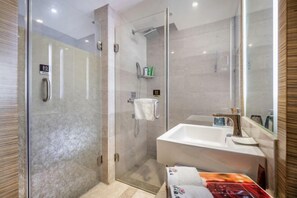 Une salle de bain moderne avec une douche à parois de verre, un lavabo avec un miroir et des articles de toilette rangés sur une étagère.
