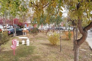 Un parking avec des voitures et une zone herbeuse avec des arbres.