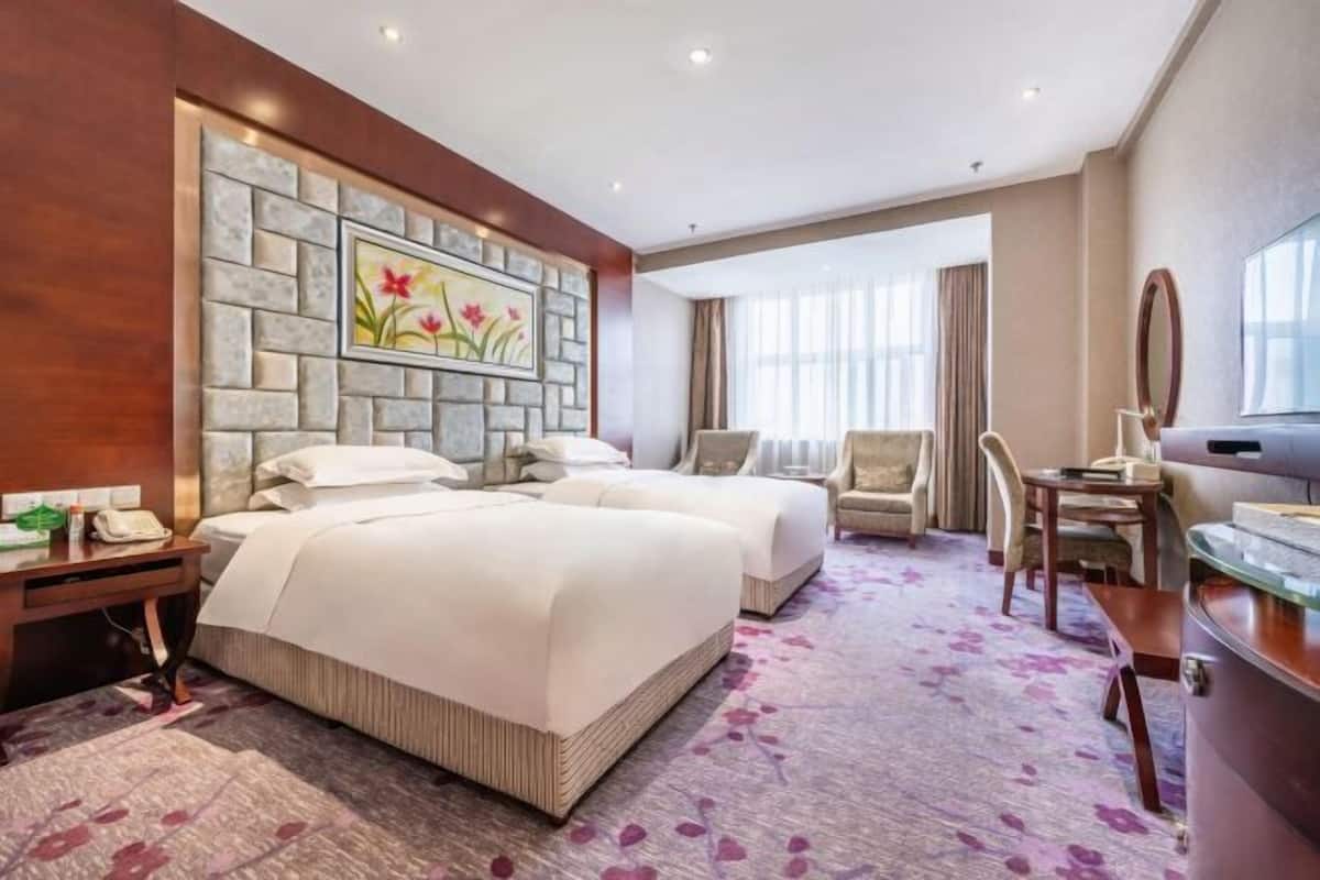 Een hotelkamer met een groot bed, twee nachtkastjes, een bureau, een stoel en een grote spiegel.
